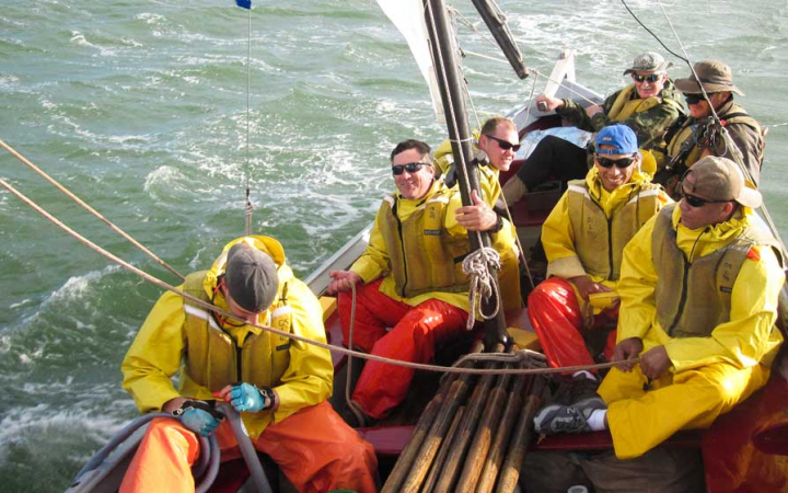 a group of veterans navigate a sailboat on an outward bound expedition